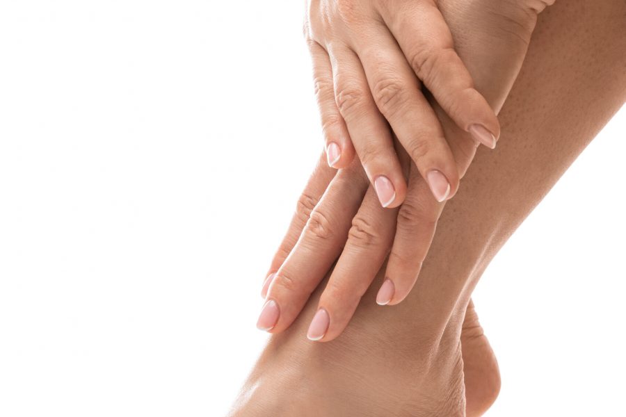 Closeup of female feet and hands with soft skin, french manicure and pedicure on white background